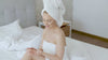 Women in towel putting on lotion white